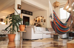Una sala de estar con un sofá, una hamaca y plantas en macetas.