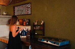Una cocina con estufa a gas, hervidor y diferentes utensilios de cocina sobre la encimera.