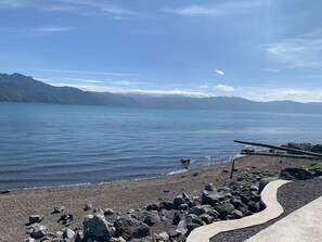 A rocky shoreline with a clear view of a calm lake and distant mountains. - Rockhouse - Steps to Water - Garden - F Optic (San Pedro La Laguna)