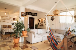 Sala de estar com sofá, rede e plantas em vasos.