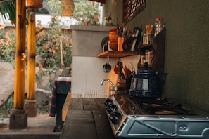 Cozinha com fogão a gás, pia e diversos utensílios e recipientes sobre o balcão.