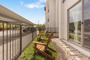 A balcony with two wooden chairs, a metal railing, and a paved walkway with stepping stones. - Luxury 1BR 1BA Apartment (Austin)