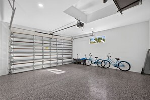 A garage with a metal gate, a ceiling fan, and a wall-mounted picture. - Brand-New Cape Coral Oasis 4BR/3BA + Heated Saltwater Pool + Waterfront (Cape Coral)