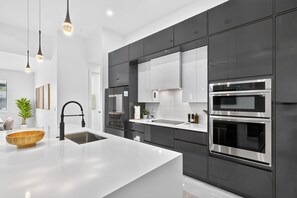 Eine moderne Küche mit Kochinsel, Edelstahlgeräten und einem minimalistischen Design.