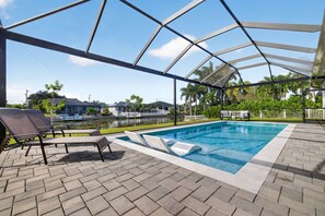 Ein überdachter Pool mit Liegestühlen, freier Aussicht auf die Umgebung und einer gepflasterten Liegefläche.