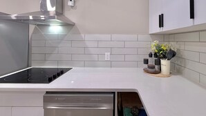 Une cuisine moderne dotée d’une cuisinière intégrée, d’une hotte en acier inoxydable et de carreaux de métro blancs sur le pare-feu.