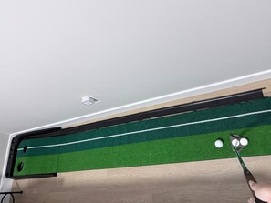 A room with a ceiling-mounted air conditioning unit, a wooden floor, and a green artificial turf area with a white line. - 2 BR Suite - Home Cinema - Location - Banff Pass (Calgary)