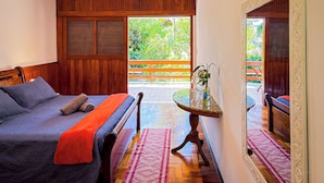 A bedroom with a bed, a table with a vase, and a view of the outdoors. - Casa Smile (Teresópolis)