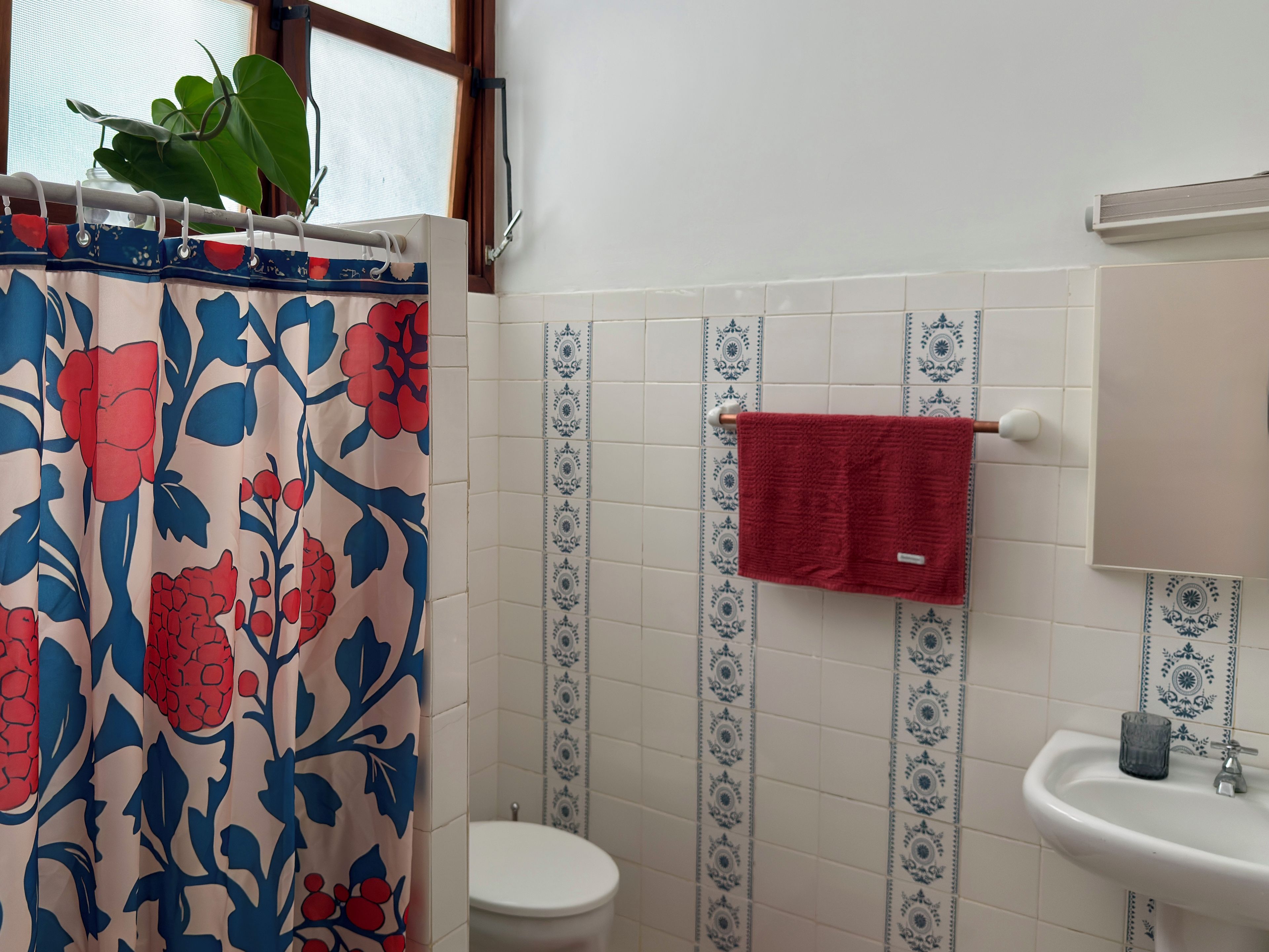 Een badkamer met douchegordijn, toilet, wastafel en handdoekrek.