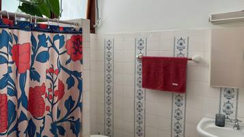 Een badkamer met douchegordijn, toilet, wastafel en handdoekrek.