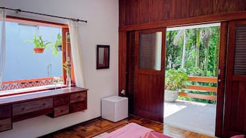 Habitación con un banco de madera, un electrodoméstico blanco pequeño, una toalla rosa y vistas al exterior con follaje.