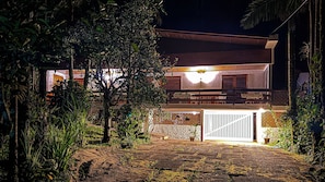 A two-story house with a balcony, surrounded by dense foliage.