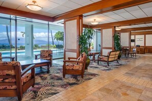 A hotel lobby with a pool view, wooden furniture, and a large plant. - Lahaina Shores Beach Resort, Ocean Views Sleeps 5 (Lahaina)