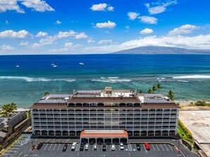 A multi-story hotel with a parking lot in front, overlooking a coastline with boats and a clear sky. - Lahaina Shores Beach Resort, Ocean Views Sleeps 5 (Lahaina)