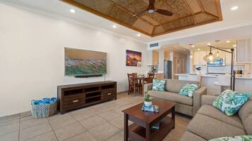 A living room with a sofa, coffee table, TV, and artwork on the wall.