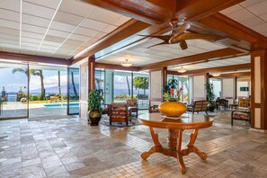 A spacious lobby with a large wooden table, comfortable seating, and a view of the ocean. - Lahaina Shores Beach Resort, Ocean Views Sleeps 5 (Lahaina)