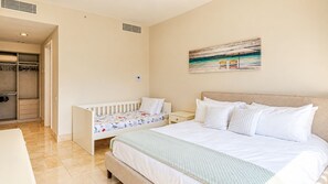 A bedroom with a single bed, a crib, a walk-in closet, and a painting on the wall. - Serene Retreat 2BR in Plaza Puntarena (Río Hato)
