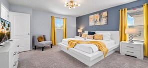Ein Schlafzimmer mit einem Bett, Nachttischen, einem Sessel und Kunstwerken an der Wand.