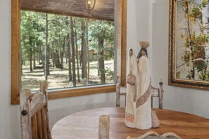 Een houten eettafel in rustieke stijl met uitzicht op een bos door een groot raam.