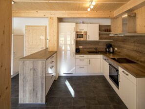 A modern kitchen with wooden cabinetry, a central island, and a built-in oven. - One-bedroom Cabin (Sankt Georgen am Kreischberg)