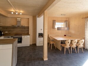Eine moderne Küche mit einer zentralen Kochinsel, eingebauten Geräten und einem Essbereich mit Holztisch und Stühlen.
