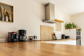 A modern kitchen with a wooden countertop, a coffee maker, a toaster, and a built-in oven.