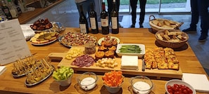 A buffet table with various food items and wine bottles.