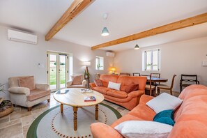 Ein geräumiges Wohnzimmer mit einer großen Couch, einem Couchtisch und einem Essbereich mit einem Holztisch und Stühlen.