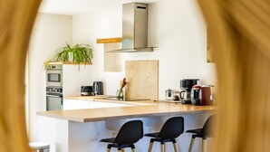 Una cocina moderna con una isla central, taburetes de bar y una planta colgante.