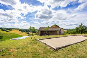 A rural property with a swimming pool, a covered outdoor area, and a view of the surrounding countryside.