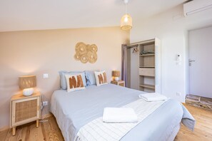 Een slaapkamer met een bed, nachtkastjes, een kledingkast en een hanglamp.