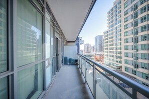 A narrow balcony with a glass railing, overlooking a cityscape with multiple high-rise buildings. - Modern 2BR Condo in Midtown Toronto with Balcony (Toronto)