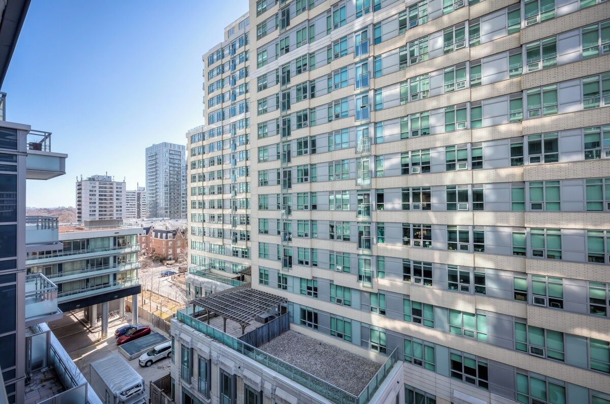 A high-rise building with multiple floors, large windows, and a parking area below.