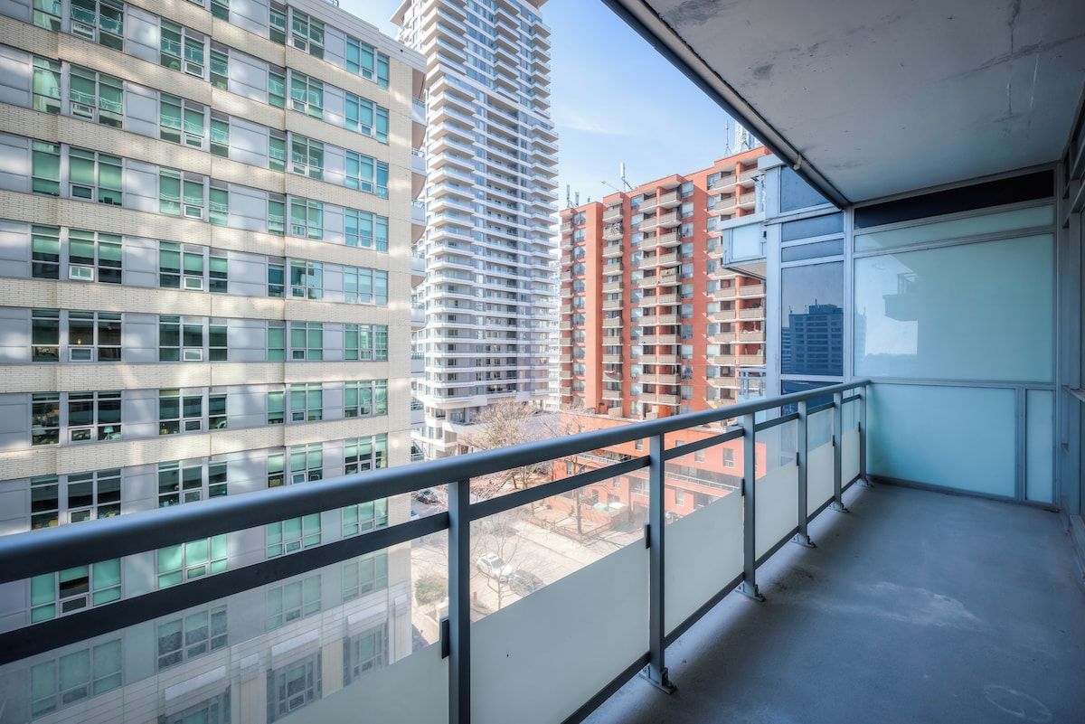 A high-rise building with multiple floors, large windows, and a balcony with a metal railing.