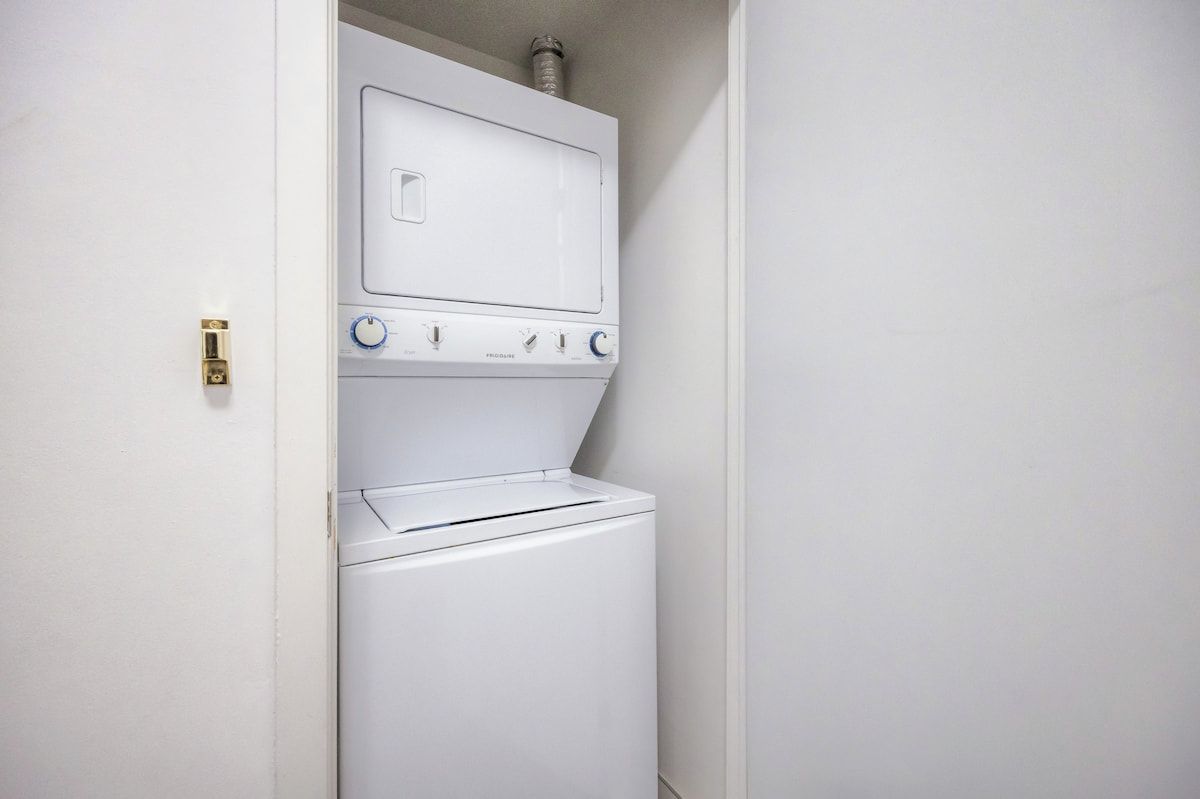 A compact, white laundry room with a washing machine and dryer stacked vertically.