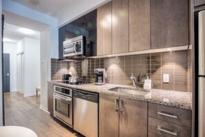 A modern kitchen with stainless steel appliances, a microwave, and a tiled backsplash.