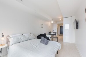 Una camera da letto moderna con un letto, un comodino e una scrivania con una sedia.