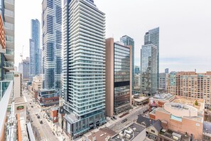 Ein Hochhaus mit moderner Glasfassade, umgeben von weiteren hohen Gebäuden in einer städtischen Umgebung.