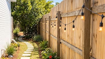 A wooden fence with a light string, a dog, and a stepping path.