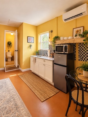 A compact kitchen with white cabinets, a microwave, and a refrigerator.