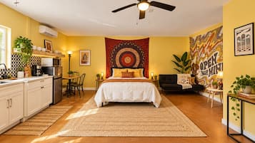 A bedroom with a bed, a ceiling fan, a tapestry, and a wall with a mural.