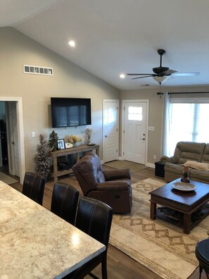 A living room with a fireplace, leather sofa, dining table, and a ceiling fan.