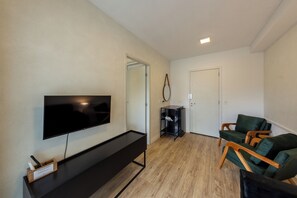 Ein modernes Wohnzimmer mit einem an der Wand befestigten Flachbildfernseher, einer schwarzen Unterhaltungsanlage und zwei grünen Polsterstühlen.