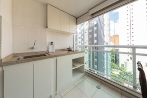 Ett modernt kök med en inbyggd diskho, en kaffebryggare och utsikt över stadsbilden genom ett stort fönster.
