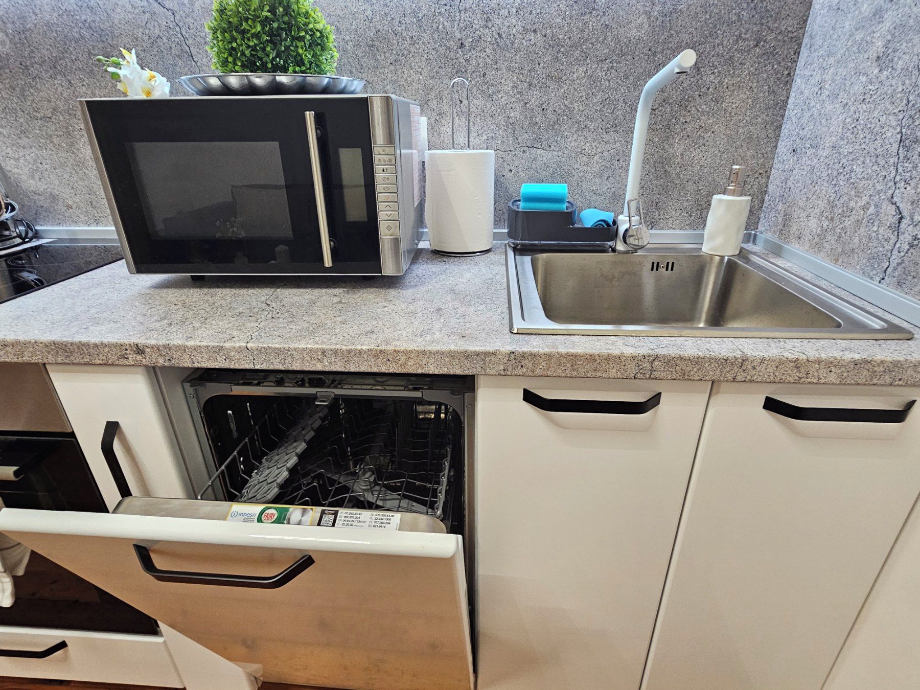 Una cocina con microondas, fregadero y lavavajillas.