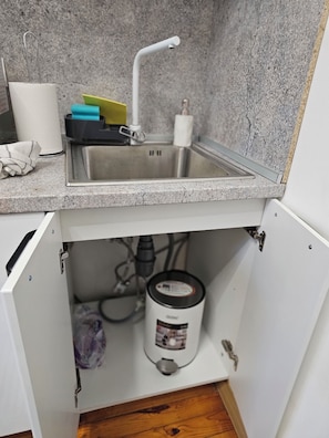 Una cocina con un lavamanos de acero inoxidable, un dispensador de toallas de papel y una cafetera.