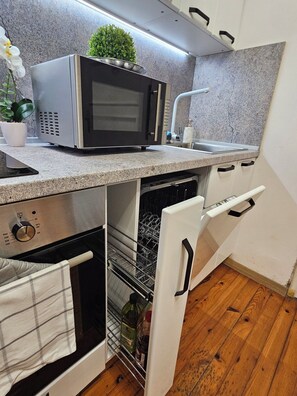 A compact kitchen with a microwave, dishwasher, and a small sink. - Apartment City center with workspace (Sofia)