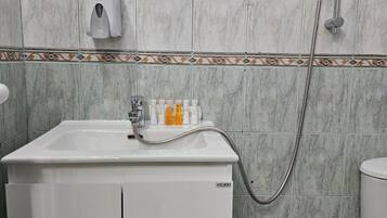 Un baño con lavabo, espejo, ducha e inodoro.