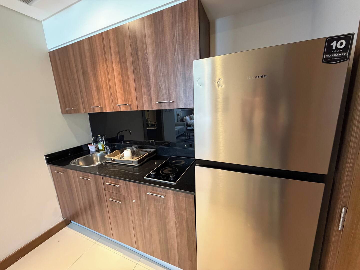 A modern kitchen with wooden cabinets, a stainless steel refrigerator, and a black countertop.