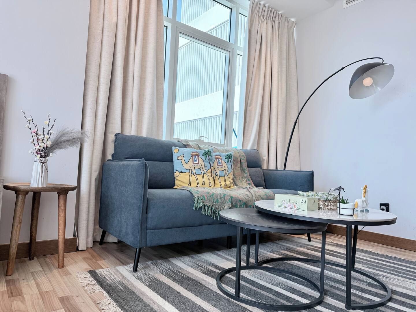 A modern living room with a sofa, a round coffee table, a lamp, and a decorative vase.